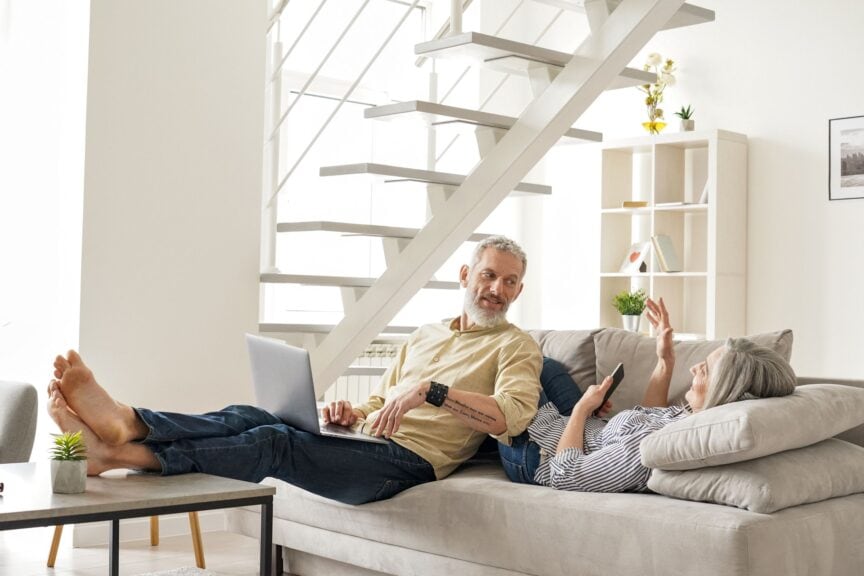 An older couple relaxing on their couch at home while having a conversation